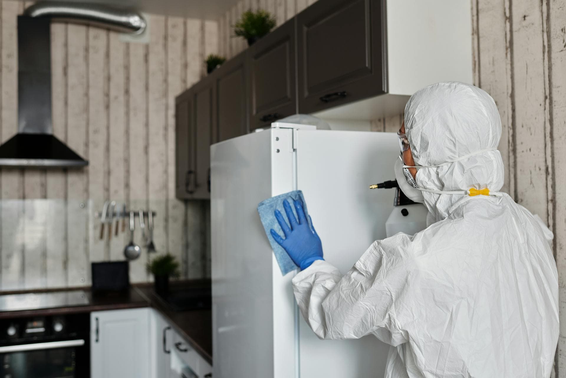 Person in protective suit performing professional pest control treatment inside a home